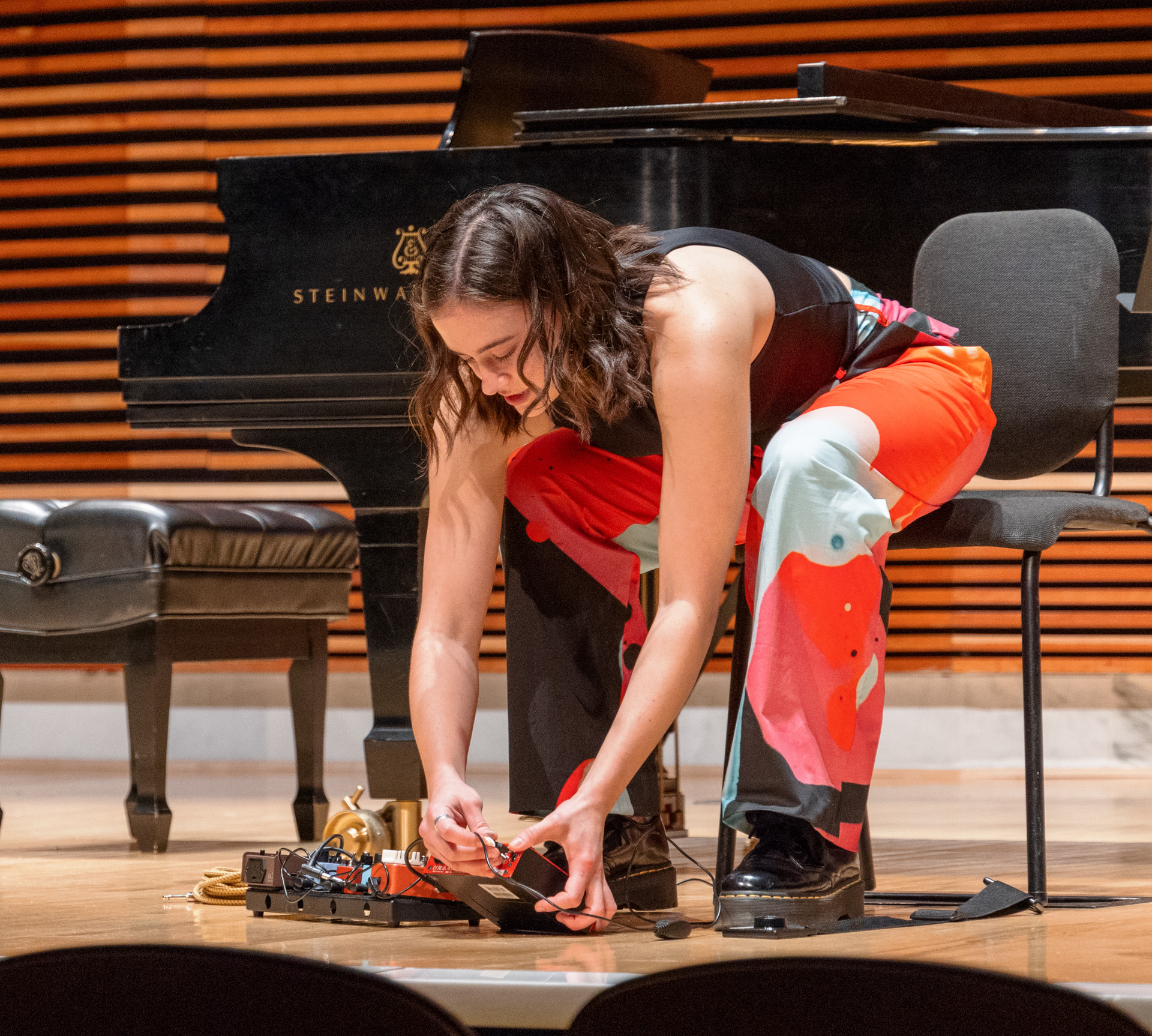 Hannah Paulus setting up effects pedals on stage for an electro-acoustic performance