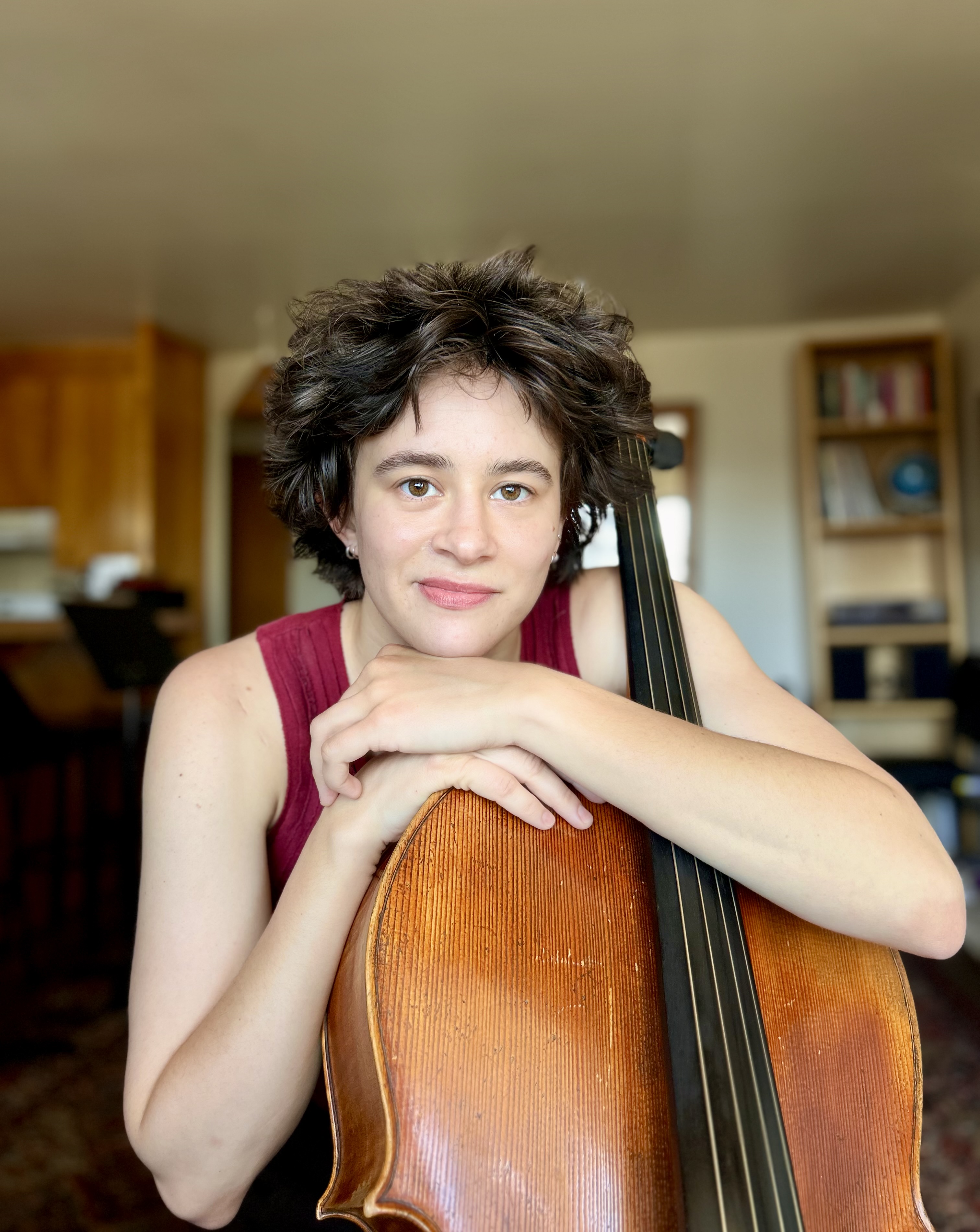 Portrait of cellist Hannah Paulus resting on her cello